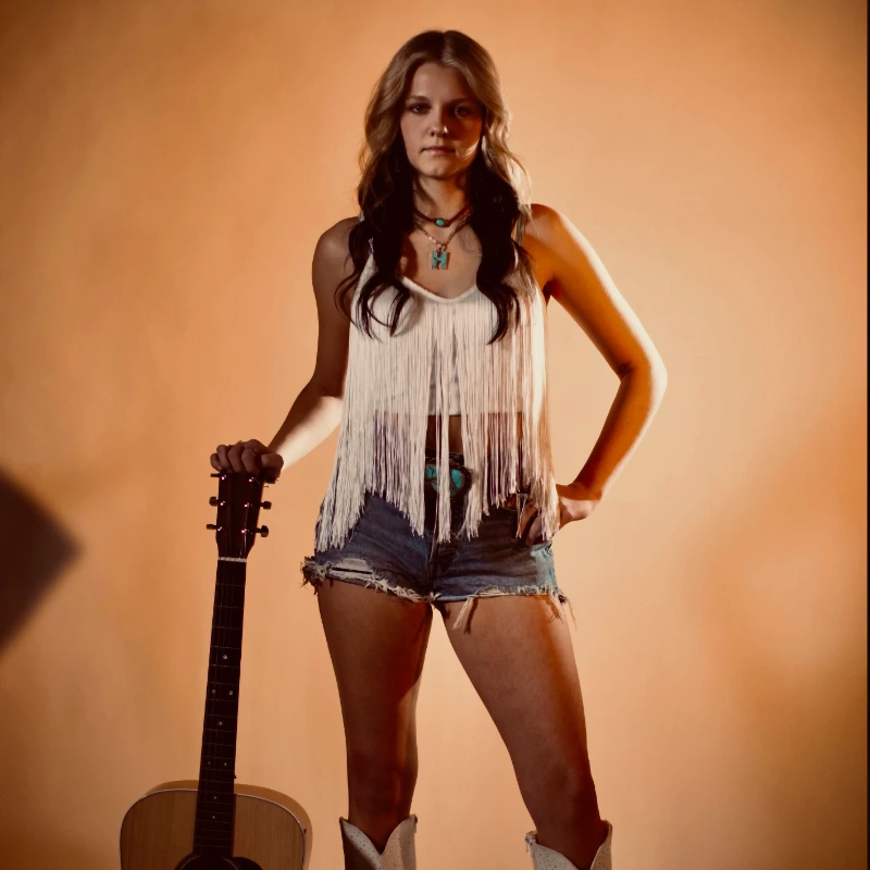 Photo of Lily standing with guitar