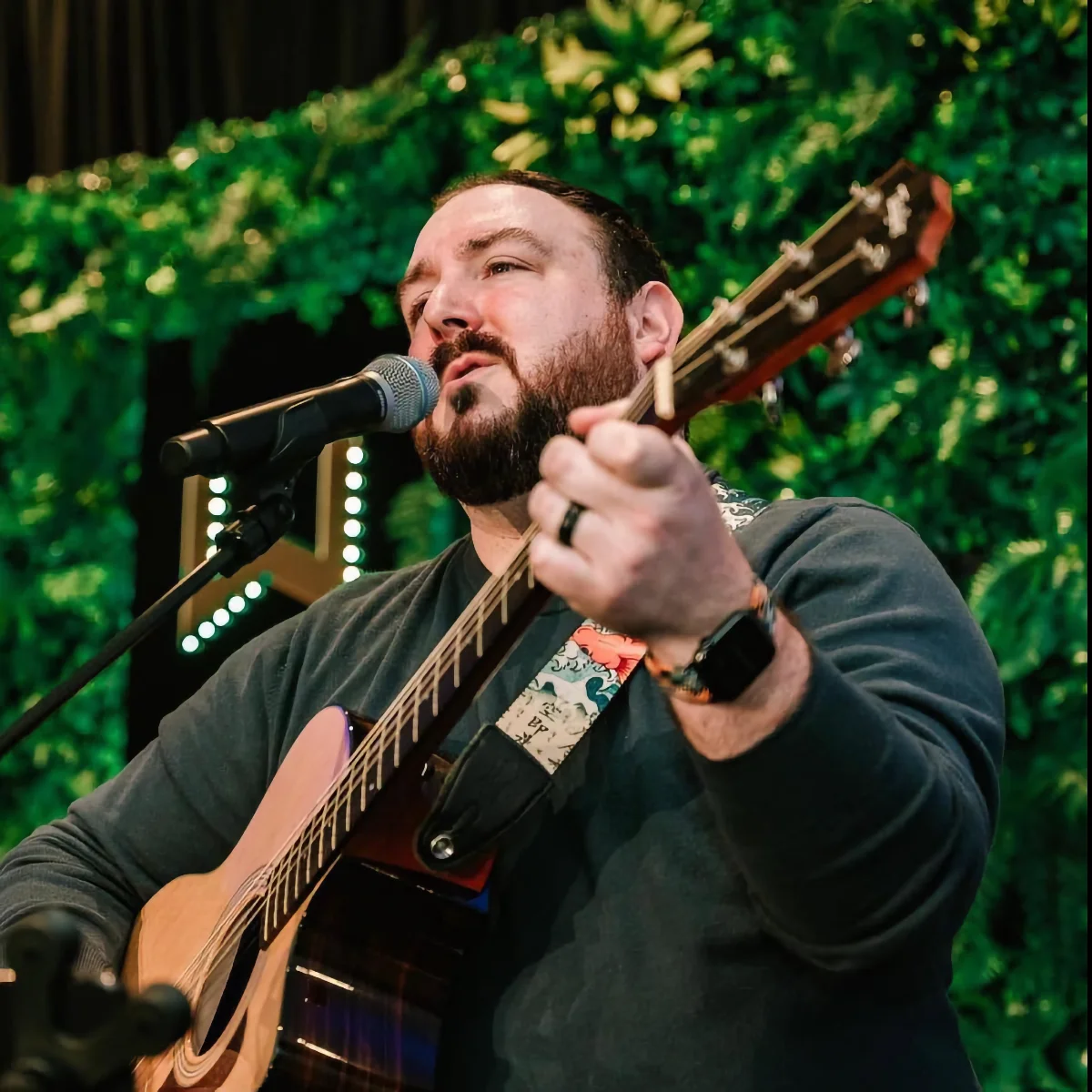 Photo of Dan Pyne playing guitar and signing on stage