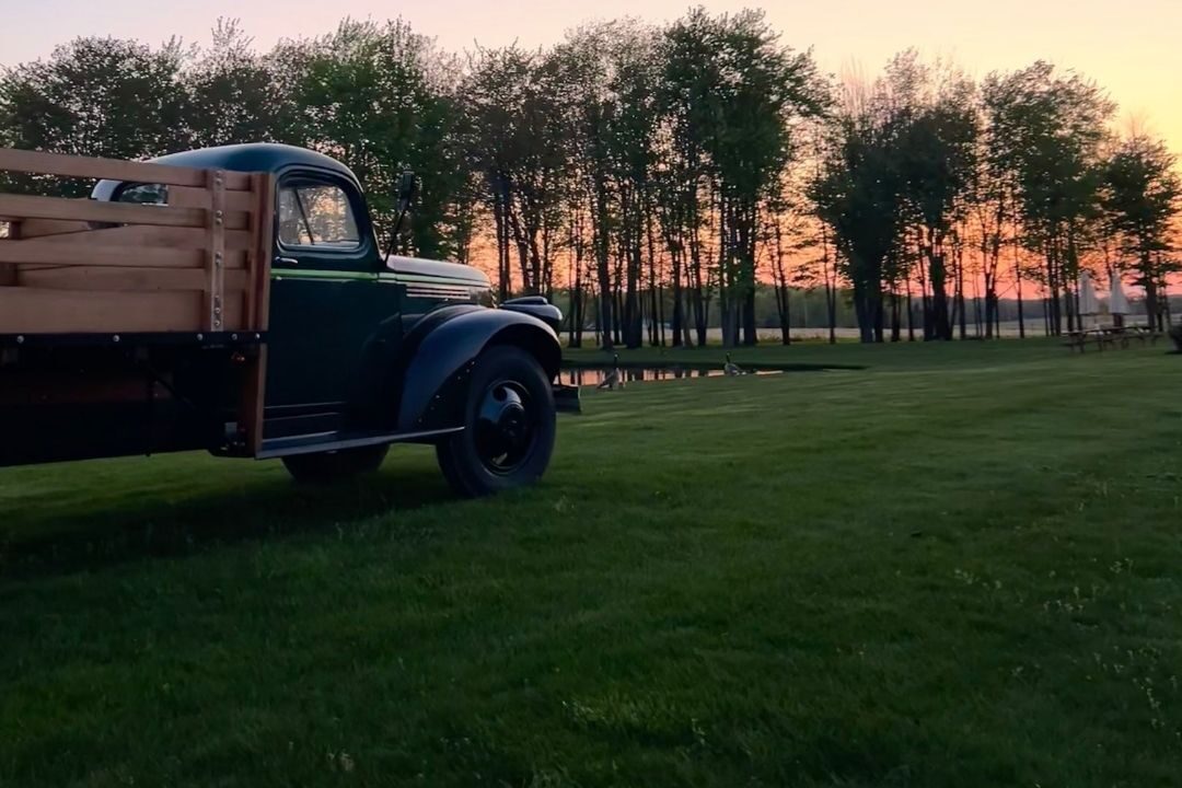 Vintage Laurentia truck on the lawn at sunset, treeline behind